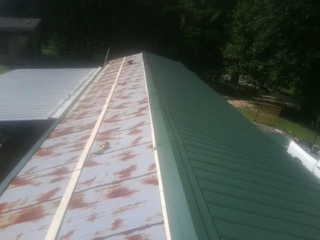 Old rusted panels beside newly installed green metal roofing — Wind Damage Roof Repair by Roofing Brothers in Myrtle Beach