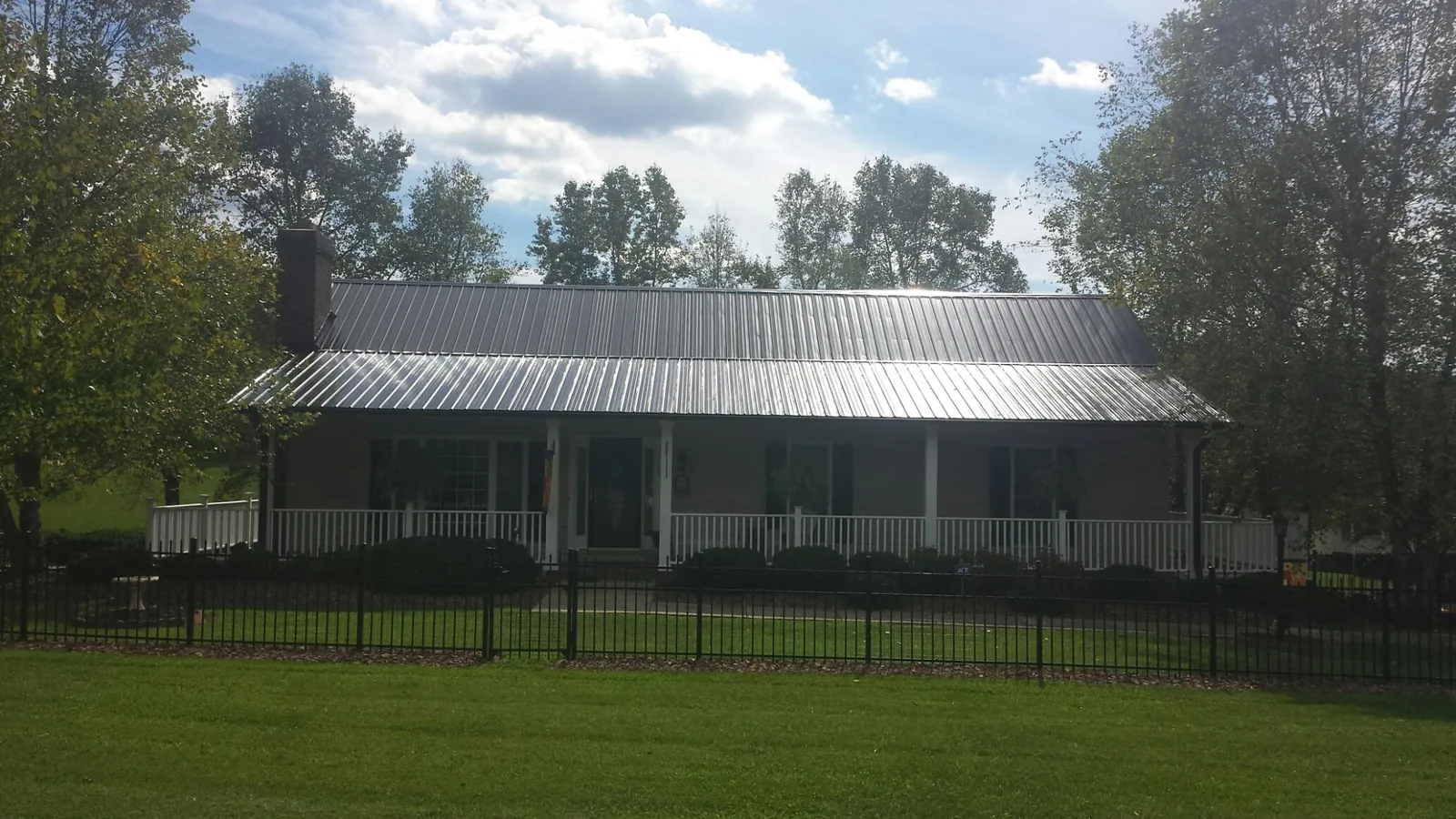 Gray metal roof on a brick ranch with a full width front porch — Gutter Guard Installation work by our crew in Myrtle Beach
