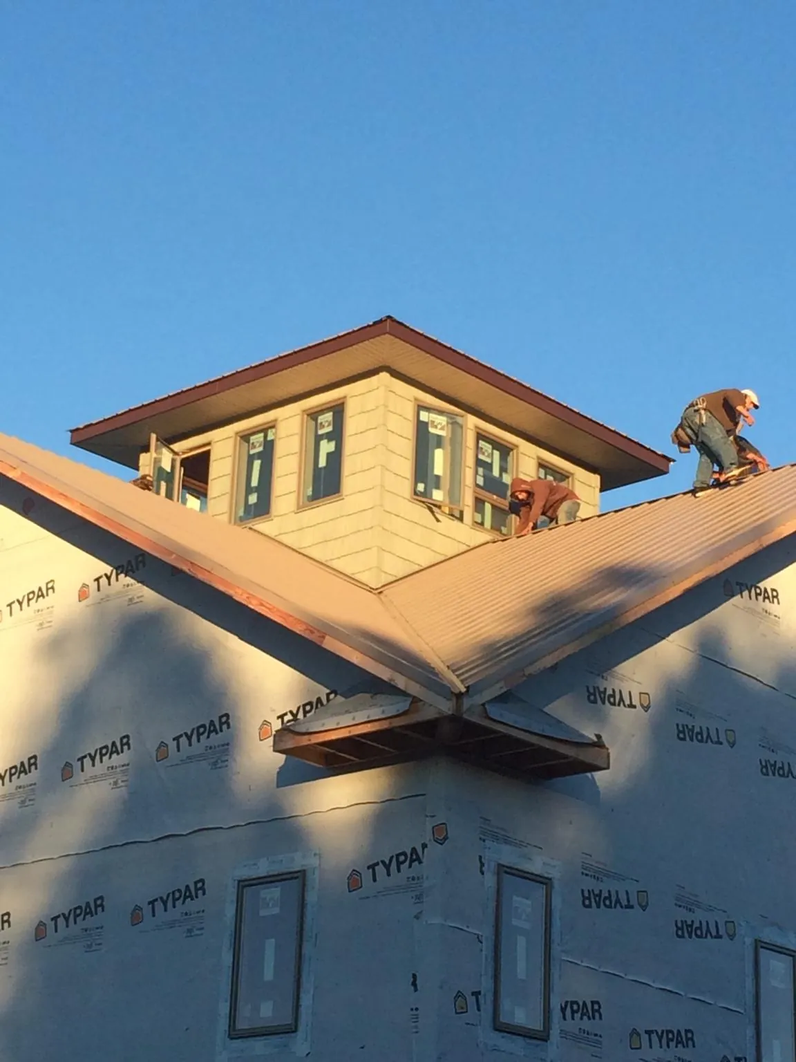 Roofers working around a rooftop cupola on a new metal roof at sunset — Roof Waterproofing in Myrtle Beach by Roofing Brothers